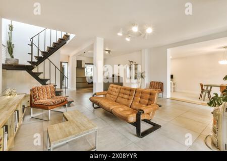 Ein gut beleuchtetes, modernes Wohnzimmer mit offenem Stockwerk, Treppe, Essbereich und Küche. Stockfoto