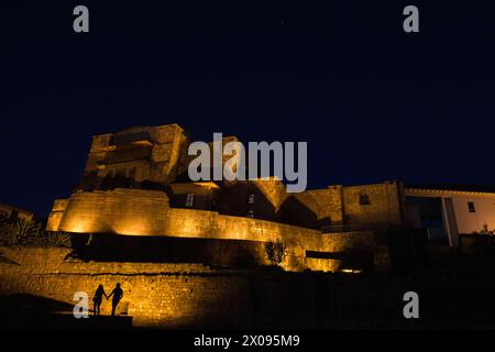 Coricancha und das Kloster von Santo Domingo in Cusco Peru werden abends beleuchtet, während Touristen und Touristen die Silhouetten sehen Stockfoto