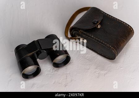 Antikes Fernglas mit Lederetui, isoliert auf einem sauberen weißen Hintergrund, bietet viel Platz für Text oder Designelemente. Perfe Stockfoto