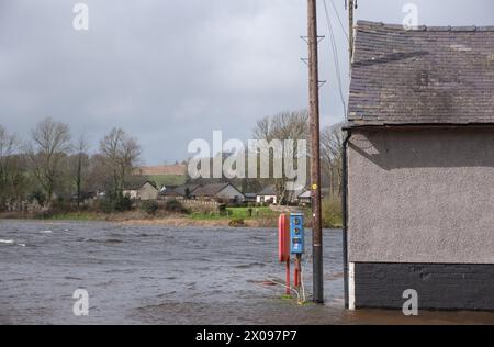 Der Fluss Nith verursachte am 7. April 2024 eine Überschwemmung am Kingholm Quay in Schottland. Ein Paar beobachtet, wie der Wasserspiegel steigt, während er in ihrem Garten steht. Stockfoto