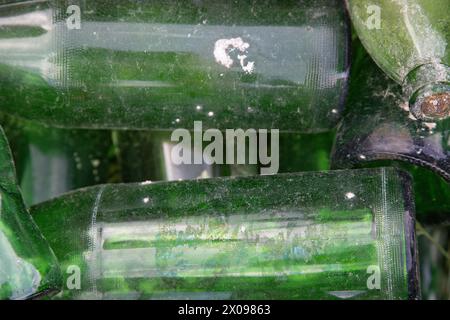 Nahaufnahme von leeren, gebrauchten und schmutzigen grünen Glasflaschen, die zufällig zurückgelassen wurden. Abstrakter Hintergrund, Konzept von Recycling, Wiederverwendung, Wiederherstellung. Stockfoto