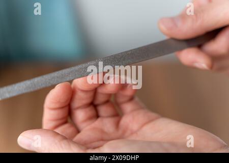 Detaillierte Nahaufnahme der Hände einer Frau, die einer professionellen Maniküre unterzogen wird, wobei der Schwerpunkt auf dem Feilprozess liegt, während die Nägel sorgfältig geformt und geformt sind Stockfoto