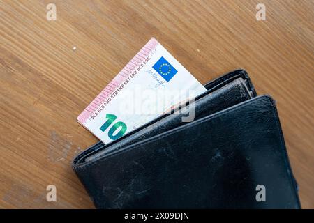 Auf einem Holztisch befindet sich eine schwarze Geldbörse, die ein einfaches, aber unverzichtbares Tagesgericht präsentiert. Stockfoto