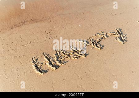 Das Wort „GLÜCK“ steht auf der Oberfläche des Sandstrandes und symbolisiert Freude, Positivität und die einfachen Freuden des Lebens und schafft eine herzerwärmende Atmosphäre Stockfoto