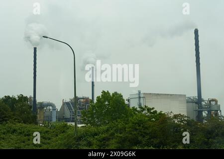 Eine Fabrik, die Rauch aus ihren hohen Stapeln in den Himmel bläst, zeigt industrielle Aktivität und Verschmutzung. Stockfoto