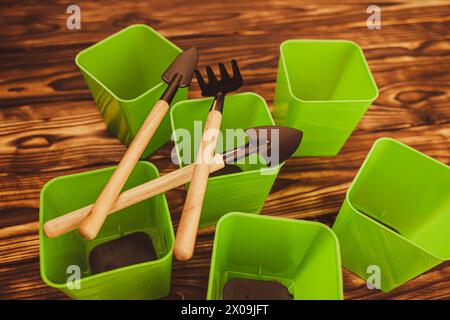 Eine Sammlung von Miniatur-Gartenwerkzeugen auf einem Holztisch, einschließlich Schaufeln, Rechen und Töpfen für Setzlinge Stockfoto