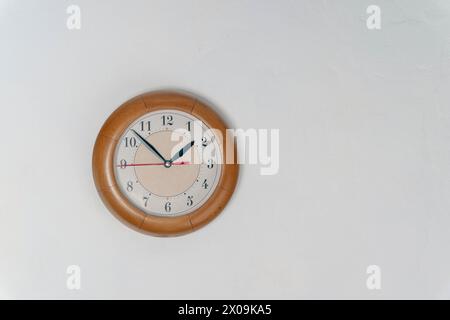 Eine Uhr hängt an der Wand eines Raumes, umgeben von Möbeln und Dekor. Zeit bei 1 Stunde und 50 Minuten Stockfoto