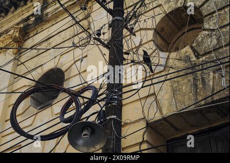 08.11.2015, Yangon, Myanmar, Asien - Ein Vogel sitzt auf einer Stromleitung inmitten von Kabelgewirr an einem Versorgungsmast im Stadtzentrum. Stockfoto