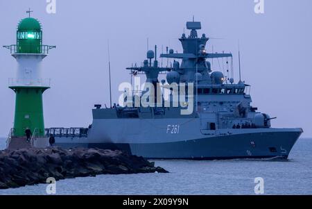 Rostock, Deutschland. März 2024. Ein Militärschiff der Deutschen Marine passiert das Leuchtfeuer am Westpier von Warnemünde in Richtung Marinestützpunkt hohe Düne. Quelle: Jens Büttner/dpa/Alamy Live News Stockfoto