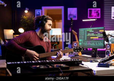 Musiktechniker spielt neue Melodien auf Akustikgitarre und nimmt mit der daw-Software-Schnittstelle auf, bereitet sich auf die Mischen- und Mastering-Session vor. Junger Songwriter, der Soundtracks mit Instrument erstellt. Stockfoto