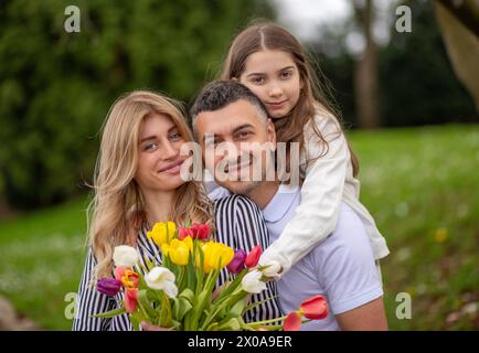 Glückliche Familie, die sich im Park umarmt, lächelt und die gemeinsame Zeit genießt Stockfoto