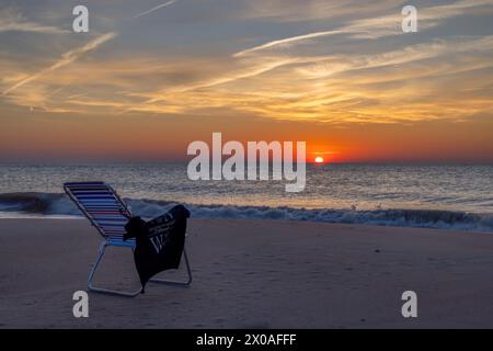 Leerer, einladender Stuhl am farbenfrohen Sonnenaufgang, Rehoboth Beach, Delaware Stockfoto