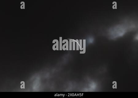 Partielle Sonnenfinsternis - Mond bedeckt Sonne, dunkle Wolken, himmlisches Drama - Halbmondsonne - atmosphärische Stimmung. Aufgenommen in Toronto, Kanada. Stockfoto