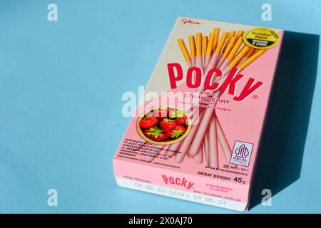 Wonosobo, Indonesien 23. April 2023: Pocky Snacks mit Erdbeergeschmack in rosa Verpackung. Vor blauem Hintergrund. Stockfoto