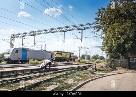 Bild eines Menschen, der im Bahnhof von Batajnica in Serbien wartet, mit einem Güterzug im Hintergrund Stockfoto