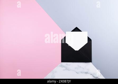 Draufsicht des schwarzen Umschlags, weiße Karte auf farbenfrohem Hintergrund. Blauer, rosafarbener und Marmorhintergrund. Pastellfarbene Tapeten, Marmorstruktur, Kopier-Spa Stockfoto