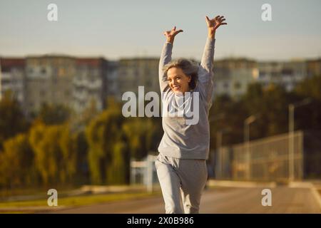 Porträt einer hochgeregten glücklichen Frau nach erfolgreichem Morgentraining im Stadtpark. Stockfoto
