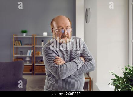 Porträt eines ernsten älteren Mannes, der mit gefalteten Armen steht Stockfoto