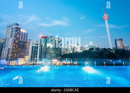 Atemberaubender Blick auf die Wolkenkratzer der Stadt KL, nachts hell beleuchtet, eleganter Pool im Vordergrund mit atemberaubendem Panoramablick Stockfoto