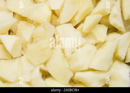 Eine Nahaufnahme frisch geschnittener roher Kartoffeln mit kleinen Bläschen, die zum Kochen einweichen. Zubereitung von Lebensmitteln. Stockfoto