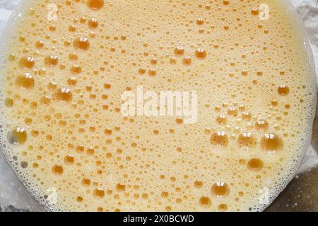 Blick von oben auf eine Kristallschale mit schaumigen Eierblasen aus frisch geschlagenen Eiern. Essen. Stockfoto