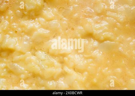 Nahaufnahme einer cremigen Textur und eines goldenen Farbtons aus geschlagenen Eiern, verschwendeten Kartoffeln und Zwiebeln schaffen eine abstrakte Landschaft. Nahrung und Textur. Stockfoto