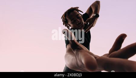 Junger Mann mit Dreadlocks tanzt energetisch zum Rhythmus der Musik in einem Studio. Expressiv und künstlerisch bewegt er sich anmutig mit geschlossenen Augen, Hand Stockfoto