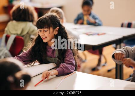 Eine Grundschulschülerin sitzt an ihrem Schreibtisch und macht ihre Schularbeit. Mädchenschulung in einem Co-Ed-Kinderentwicklungszentrum. Stockfoto