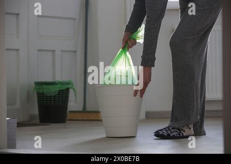 Hausfrau wirft Müll weg, nimmt Plastikmüllbeutel aus dem Mülleimer in der Wohnung Stockfoto