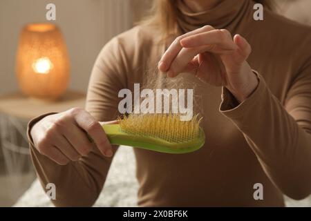 Eine Frau, die eine Haarbürste mit Haarausfall hält. Haarausfall Stockfoto