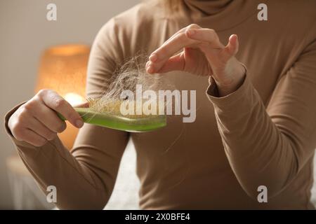 Eine Frau, die eine Haarbürste mit Haarausfall hält. Haarausfall Stockfoto