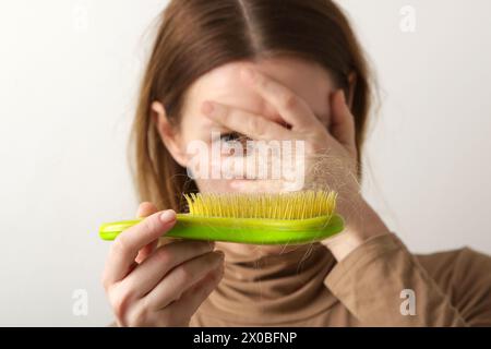 Eine Frau, die eine Haarbürste mit Haarausfall hält. Haarausfall Stockfoto