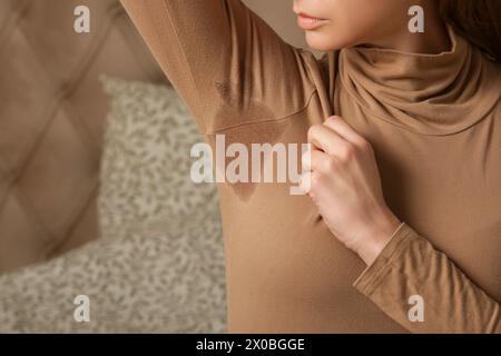 Nahaufnahme einer Frau in beigem Baumwoll-Rollkragenkragen mit Schweißfleck unter der Achselhöhle Stockfoto