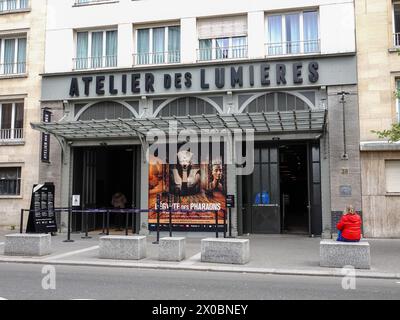 Menschen, vor dem Atelier des Lumières, immersive Kunstausstellung im 11. Arrondissement mit einem großen Poster, das das Ägypten der Pharaonen darstellt. Stockfoto