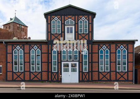 Historische Seminarturnhalle am Stade, Niedersachsen, ehemaliges Fitnessstudio, nutzte heute einen kulturellen Veranstaltungsort. Der Kirchturm der Wilhadi-Kirche hinten Stockfoto