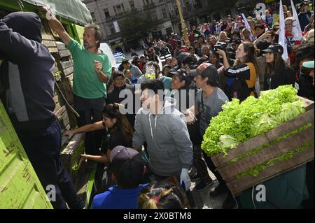 Buenos Aires, Argentinien. April 2024. Eine Gruppe von Menschen händigt Holzkisten mit Obst und Gemüse vor dem argentinischen Kongress in Buenos Aires. Hunderte von Menschen versammeln sich vor dem argentinischen Nationalkongress, um kostenlos verschiedene Früchte, Gemüse und Pflanzen direkt von den landwirtschaftlichen Erzeugern der UTT (Land Workers Union) zu erhalten, die sich aufgrund der Wirtschaftskrise im April in diesem Land befinden. Quelle: SOPA Images Limited/Alamy Live News Stockfoto