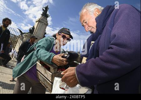 Buenos Aires, Argentinien. April 2024. Eine Frau übergibt eine Aubergine in die Tasche eines älteren Mannes vor dem argentinischen Kongress in Buenos Aires. Hunderte von Menschen versammeln sich vor dem argentinischen Nationalkongress, um kostenlos verschiedene Früchte, Gemüse und Pflanzen direkt von den landwirtschaftlichen Erzeugern der UTT (Land Workers Union) zu erhalten, die sich aufgrund der Wirtschaftskrise im April in diesem Land befinden. Quelle: SOPA Images Limited/Alamy Live News Stockfoto