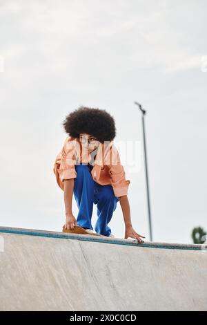 Ein junges afroamerikanisches Mädchen steht selbstbewusst auf einem Skateboard und verfeinert ihre Fähigkeiten in einem Skatepark. Stockfoto