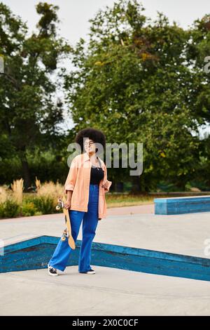 Eine junge Afroamerikanerin mit einem voluminösen Afro steht selbstbewusst in einem belebten Skatepark, bereit für die Rampen. Stockfoto