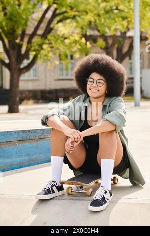 Eine stilvolle junge Afroamerikanerin mit einer voluminösen Afro-Frisur sitzt gemütlich auf einem Skateboard in einem pulsierenden Skatepark. Stockfoto