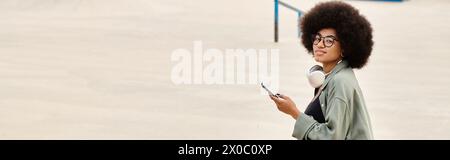 Eine stilvolle Frau mit Afro-Frisur, die ein Handy benutzt. Die urbane Szene fängt ihr Wesen ein, während sie sich mit Technologie verbindet. Stockfoto