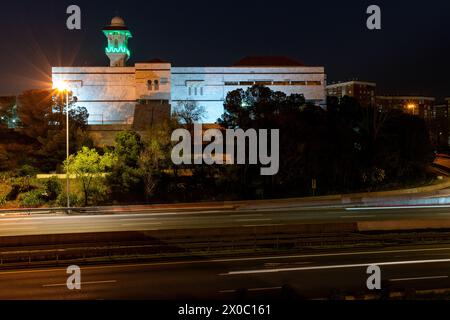 Eine majestätische weiße Moschee mit einem hoch aufragenden, beleuchteten Minarett durchdringt den Nachthimmel, seine Fenster leuchten mit warmem Licht. Nach Dem Ramadan. Grüne Farbe Stockfoto