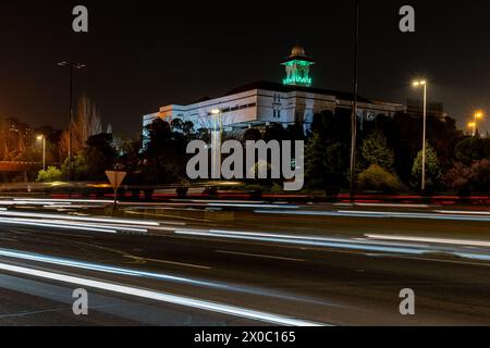 Eine majestätische weiße Moschee mit einem hoch aufragenden, beleuchteten Minarett durchdringt den Nachthimmel, seine Fenster leuchten mit warmem Licht. Nach Dem Ramadan. Grüne Farbe Stockfoto