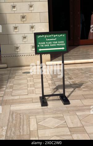 Sultan Qaboos Grand Moschee hölzernes kunstvolles zweisprachiges Schild „Bitte legen Sie Ihre Schuhe in die Schuhregale bereit“ Muscat Oman Stockfoto