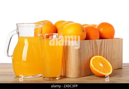Frische Orangen in Kiste und Saft auf Holztisch vor weißem Hintergrund Stockfoto