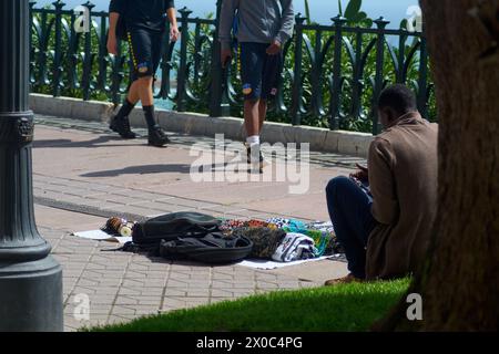 Tarragona, Spanien - 11. April 2024: Intimer Moment der Pause und der Betrachtung eines illegalen Verkäufers von handgefertigten Waren in der Stadt Tarragona Stockfoto