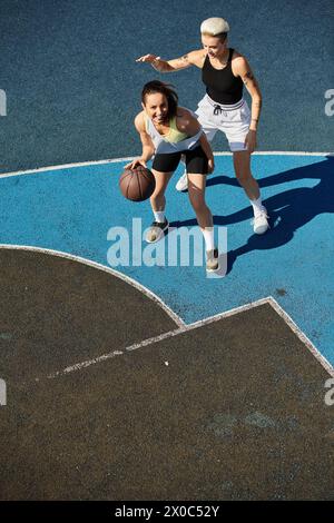 Eine Frau spielt energisch Basketball auf einem Platz und zeigt in einem Sommerspiel ihre Leichtathletik und Teamarbeit. Stockfoto