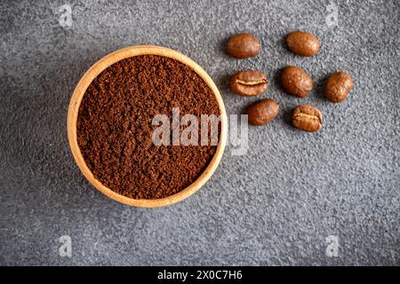 Kaffeebohnen mit einer Schüssel gemahlenen Kaffees auf schwarzem Hintergrund Stockfoto