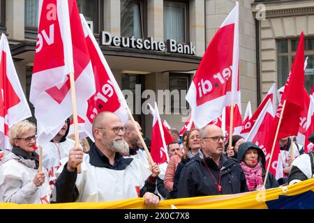 Hamburg, Deutschland. April 2024. Während eines Warnstreiks bei der Postbank stehen die Teilnehmer einer Demonstration vor einem Gebäude der Deutschen Bank während einer Interimskundgebung. Der Streik ist Teil einer bundesweiten Streikwelle der gewerkschaft Verdi, um den Druck auf den Arbeitgeber in den laufenden Tarifverhandlungen zu erhöhen, nachdem die dritte Verhandlungsrunde ohne Vereinbarung beendet wurde. Quelle: Bodo Marks/dpa/Alamy Live News Stockfoto