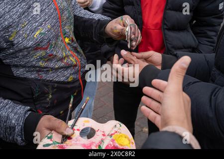 Diyarbakir, Türkei. März 2024. Die Leute bezahlen dafür, dass sie sich während einer Kundgebung ihre Gesichter malen lassen. Hunderttausende von Menschen besuchen Diyarbakir Newroz, um Newroz zu feiern, das die Ankunft des Frühlings und des neuen Jahres symbolisiert. Da es verboten ist, gelbe, grüne und rote Fahnen in Newroz zu bringen, malten die Menschen ihre Gesichter in gelben, roten und grünen Farben. (Foto: Bilal Seckin/SOPA Images/SIPA USA) Credit: SIPA USA/Alamy Live News Stockfoto